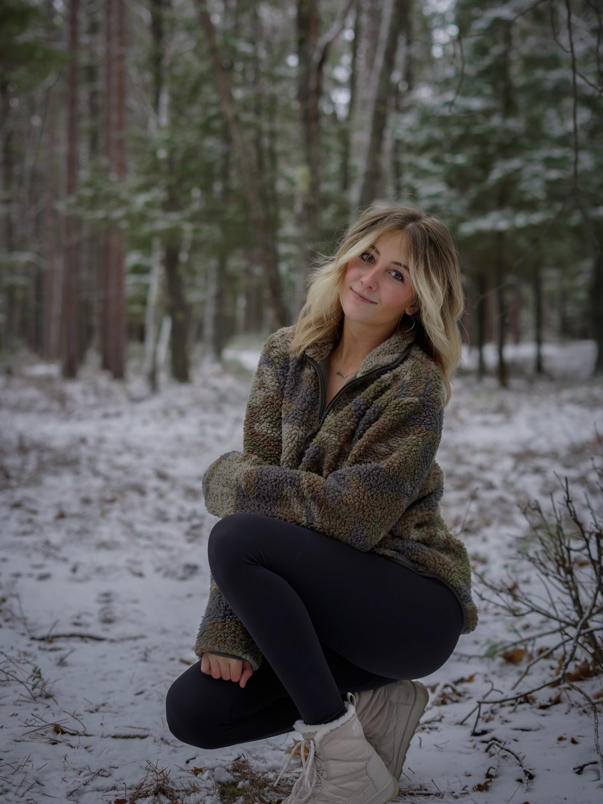 Ashlyn smiling in a snowy pine forest